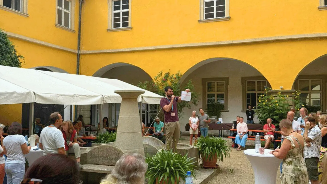 Presenter speaking to an outdoor audience at a courtyard event