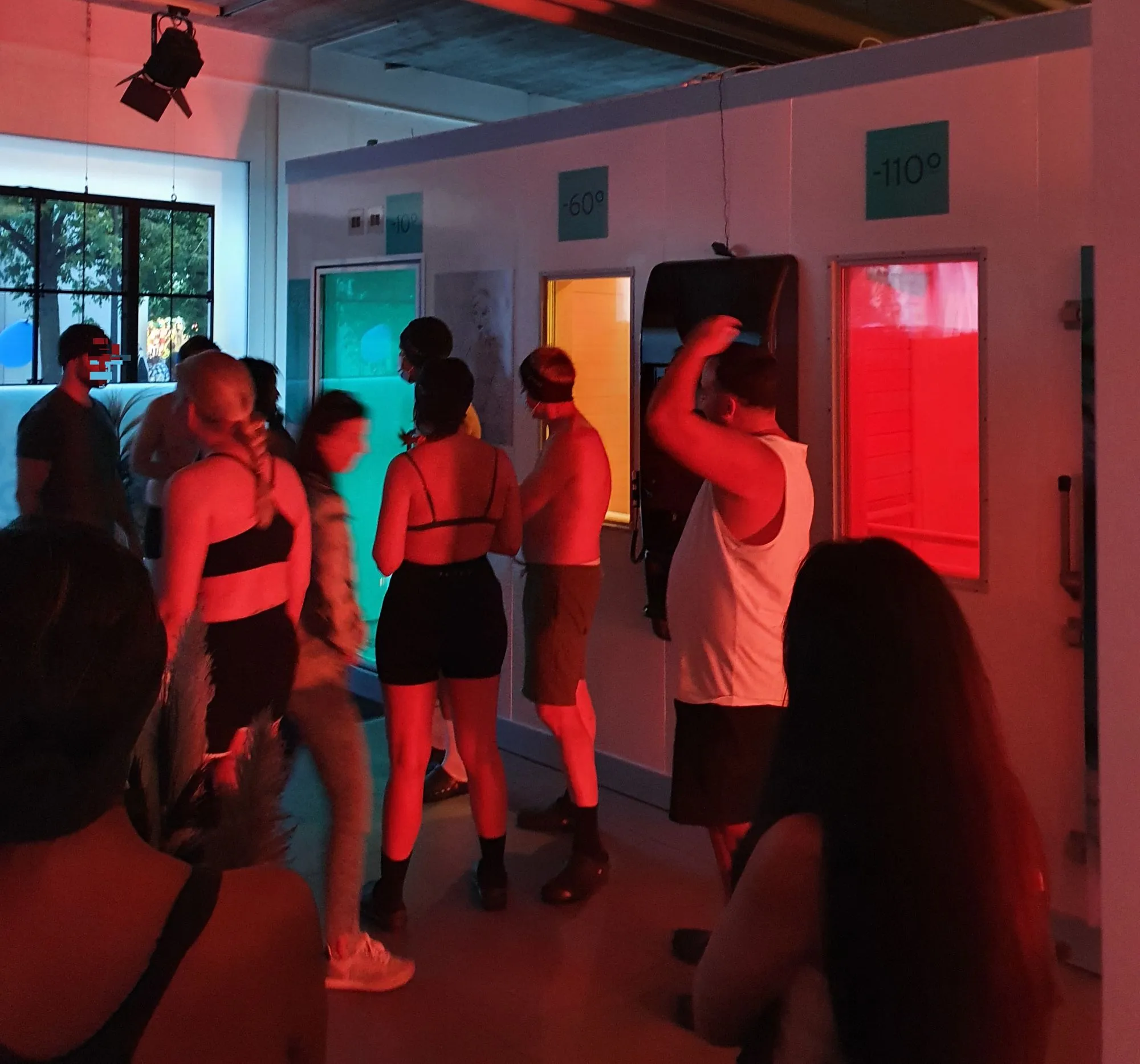 People standing in a red-lit cryotherapy room at Cyrodukt